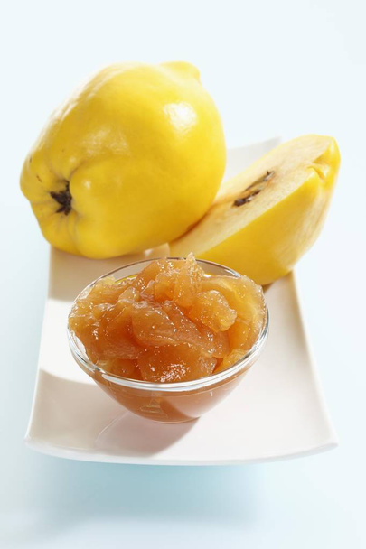 Quince (Cydonia oblonga) on a porcelain plate and a glass bowl with quince jam - Fotoğraf, Görsel