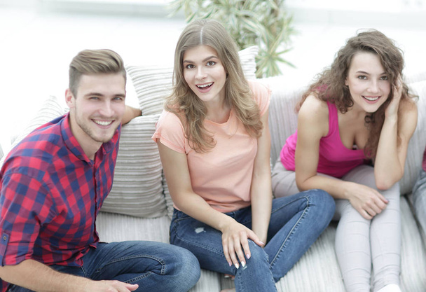 group of cheerful friends watching videos, sitting on the couch - Foto, Bild