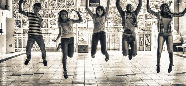 Adolescentes multi grupo étnico saltando en el patio de la escuela. Sucede.
 - Foto, Imagen