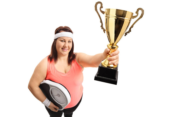 Overweight woman with a weight scale and a trophy - Foto, imagen
