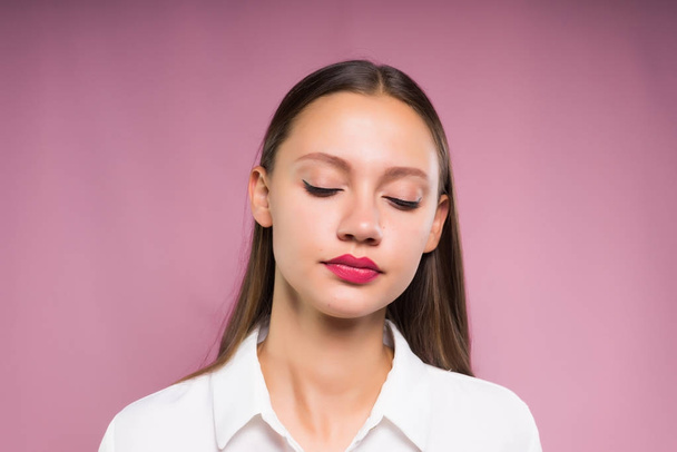 upset girl standing on a pink background closing her eyes - Foto, afbeelding