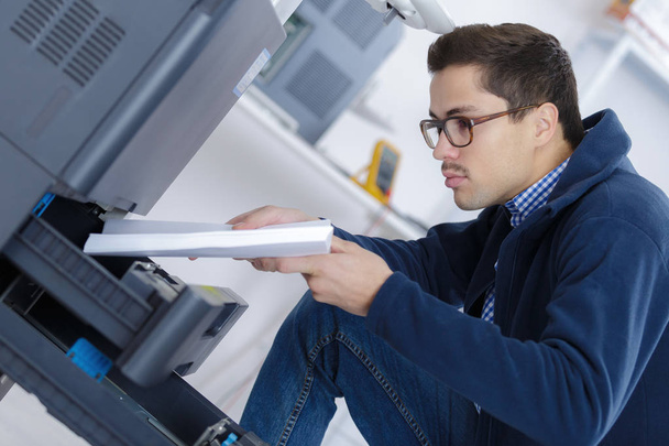 man is putting stack of paper in printing machine - Zdjęcie, obraz