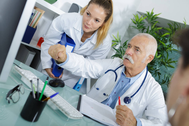 médico masculino com enfermeiro e paciente mostrando tela
 - Foto, Imagem
