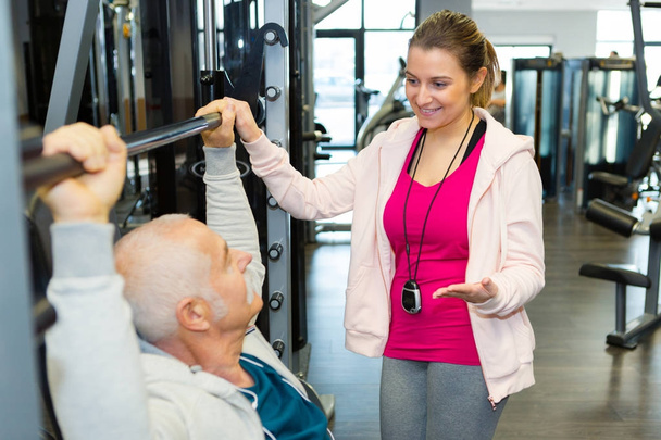 fitness instructor helping senior man using weights - Φωτογραφία, εικόνα