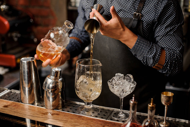 Barkeeper fügt eine Portion Sirup in das große Cocktailglas hinzu - Foto, Bild