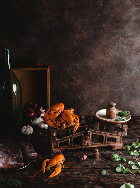 vergrote weergave van heerlijke kreeften op vintage schalen, rauwe vis en basilicum bladeren op rustieke tafelblad   - Foto, afbeelding