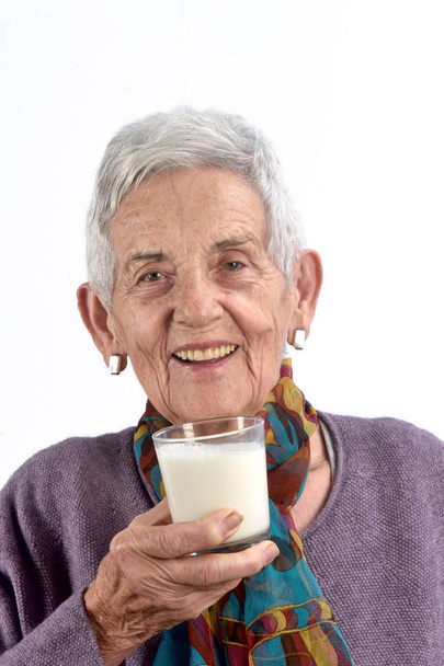 vanhempi nainen juo maitoa valkoisella taustalla
 - Valokuva, kuva