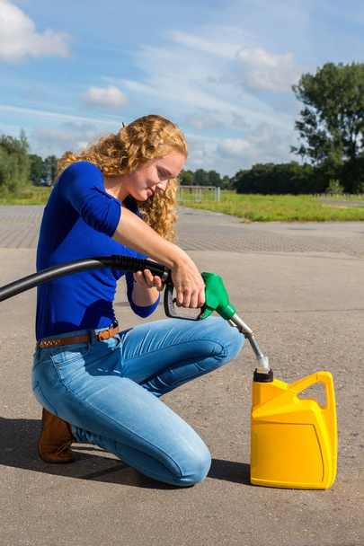 Mujer caucásica repostando bidón con gasolina
 - Foto, Imagen
