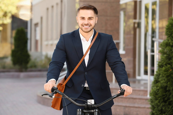 Young handsome businessman riding bicycle outdoors - Φωτογραφία, εικόνα