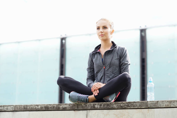 Donna giovane, in forma e sportiva seduta sul confine di cemento. Fitness, sport, jogging urbano e stile di vita sano
 - Foto, immagini
