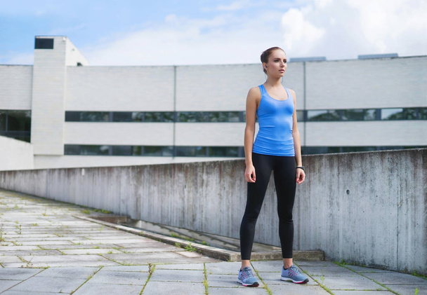 młody, dopasowanie i sportowy kobiety stojącej w pobliżu mur beton cement. Fitness, sport, miejskiego joggingu i pojęcie zdrowego stylu życia - Zdjęcie, obraz