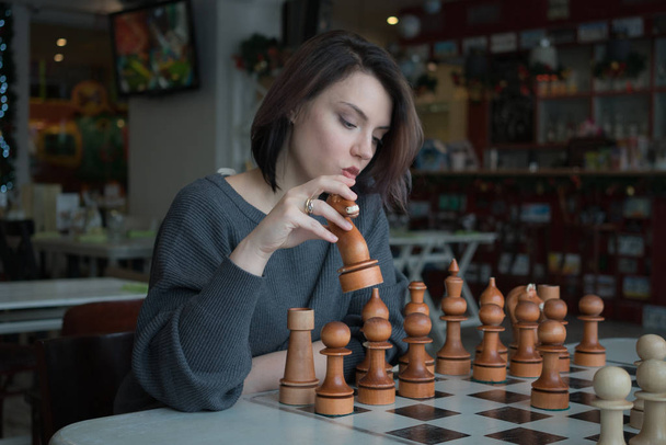beautiful girl playing chess in a cafe - Fotó, kép