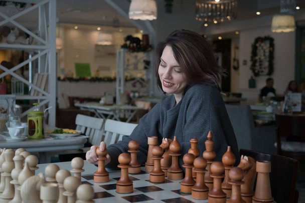 красивая девушка играет в шахматы в кафе
 - Фото, изображение
