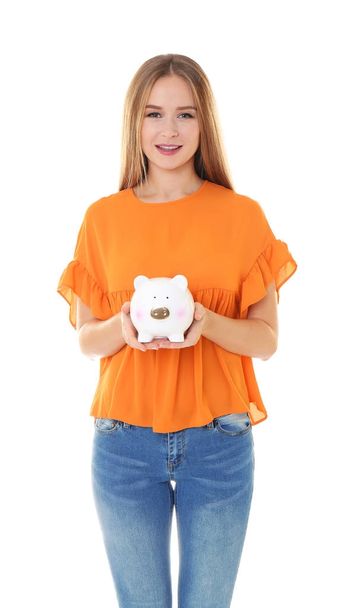 Young woman holding piggy bank on white background - 写真・画像