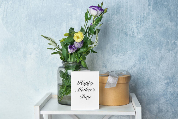 Luxe-geschenketui, bloemen en wenskaart op tafel binnenshuis. Moederdag samenstelling - Foto, afbeelding
