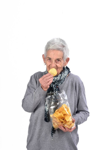 mujer mayor comiendo patatas fritas, aislado en blanco
 - Foto, Imagen