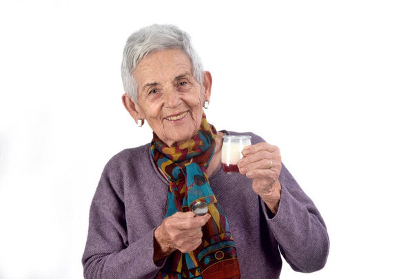 пожилая женщина ест йогурт на белом фоне
 - Фото, изображение