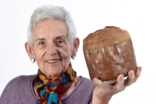 Yaşlı kadın panettone beyaz arka plan üzerinde yemek - Fotoğraf, Görsel