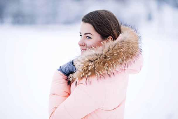 Uśmiechający się zadowolony, ładna kobieta w ciepłe zimowe kurtki na zewnątrz cieszy się podróż zimowa, wykończenie rękawice i kaptur, dużo śniegu, zawieja śnieżna do kamery, musujące światła bengal - Zdjęcie, obraz