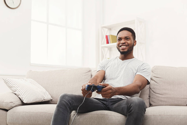 Feliz joven afroamericano en casa jugando videojuegos
 - Foto, Imagen