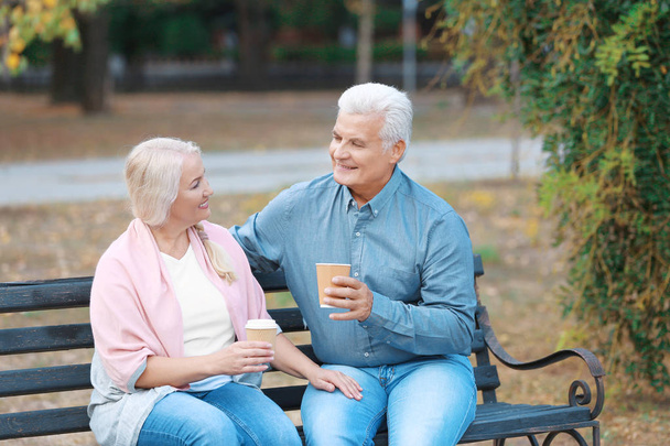 Mature couple sitting on bench outdoors - Fotó, kép