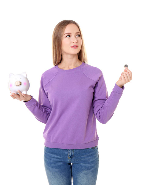 Young woman holding piggy bank and coin on white background - Foto, Imagen