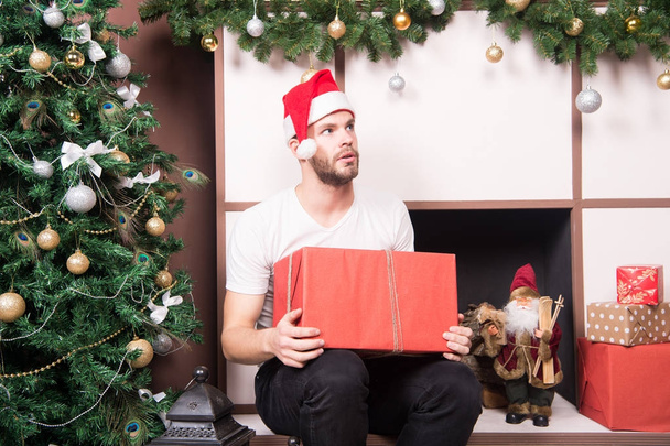 Guy with serious face in santa hat hold present box - Zdjęcie, obraz