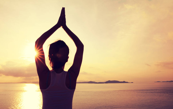 eine junge Frau praktiziert Yoga an der Küste des Sonnenaufgangs - Foto, Bild