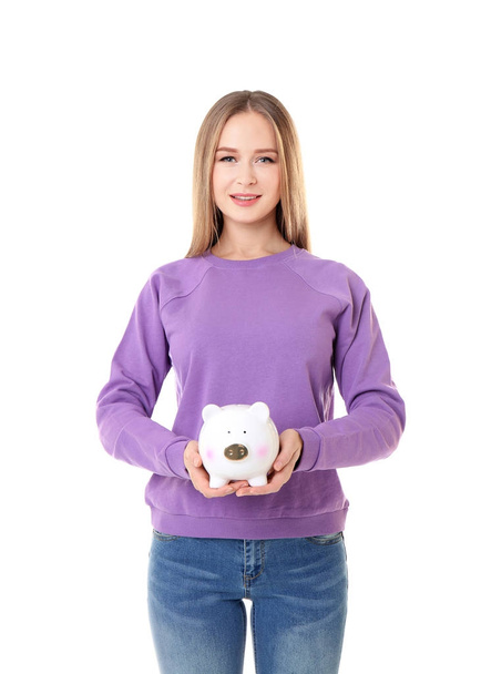 Young woman holding piggy bank on white background - Foto, imagen