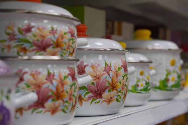 Enameled cooking pots in the supermarket on the shelf stand in a row - Photo, image