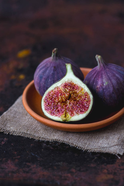 Fig fruits on clay plate on dark background. - Photo, Image