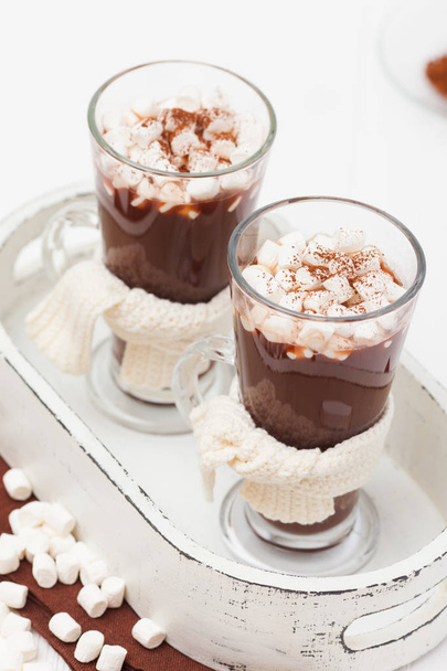 Warme cacao in glazen met marshmallow, crocahet decoraties, bruin en beige servetten op witte houten achtergrond. Warme chocolademelk. Zoet drankje. Close-up fotografie. Verticale banner - Foto, afbeelding