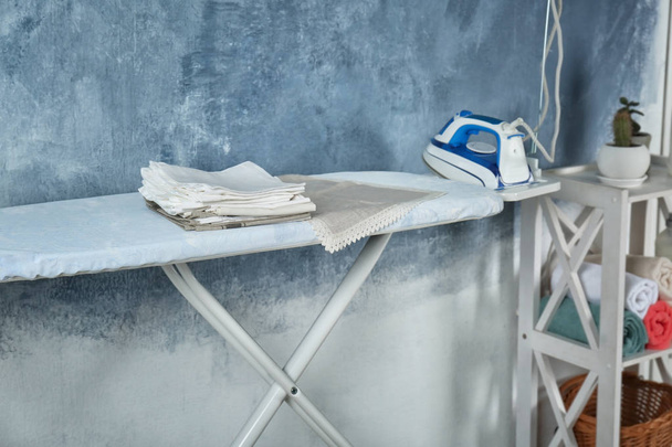 Montón de servilletas blancas limpias en la tabla de planchar en el interior
 - Foto, imagen