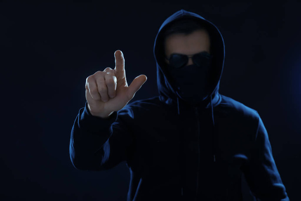 Hacker pushing button on virtual screen against dark background - Фото, изображение