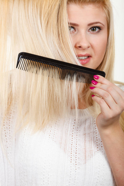Blonde woman brushing her long hair with comb - 写真・画像