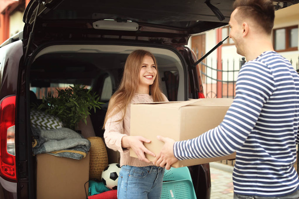 Young couple unloading boxes from their car on moving day - Foto, Bild