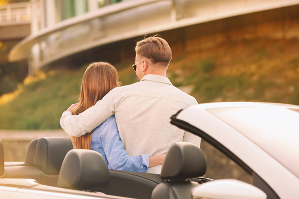 Happy young couple standing near modern car outdoors - Foto, afbeelding