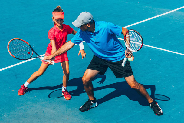 mannelijke trainer met meisje bij Tennis training - Foto, afbeelding