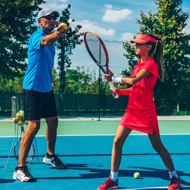 Männertrainerin mit Mädchen beim Tennistraining - Foto, Bild
