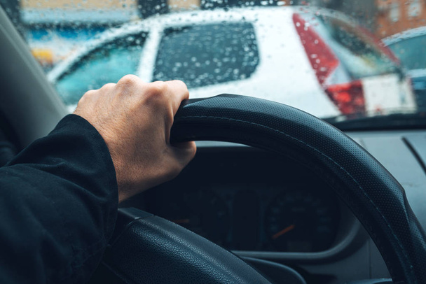 Male hand on car steering wheel in city traffic - Foto, imagen