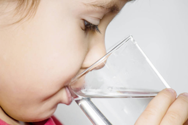 Een kind is het bezit van een glas water. Selectieve aandacht.  - Foto, afbeelding