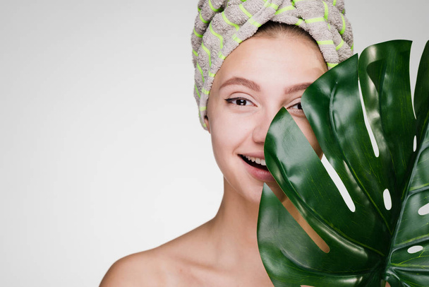 smiling young girl with a towel on her head holds a green leaf, day spa - Fotografie, Obrázek
