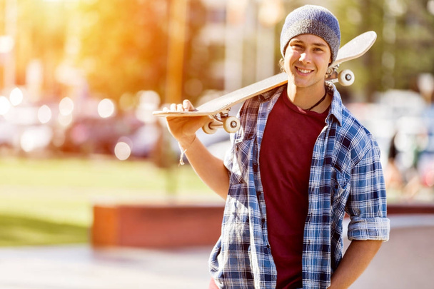 Teenage boy with skateboard standing outdoors - Φωτογραφία, εικόνα