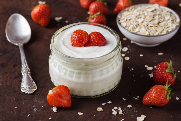 White yogurt in glass bowl with spoon and starwberries on rustic - Photo, Image