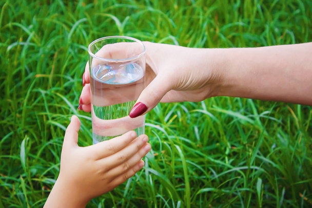 Dziecko bierze szklankę wody. Skupienie selektywne.  - Zdjęcie, obraz