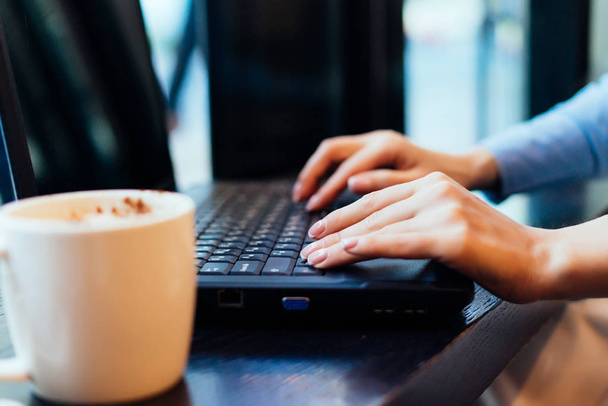 girl freelancer working on a laptop, in a cafe, on the table is a mug of delicious coffee - 写真・画像