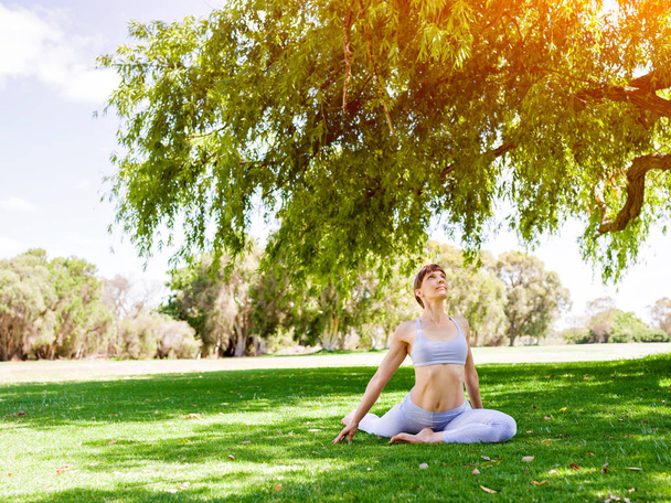 Young woman practicing yoga in the park - Foto, Bild