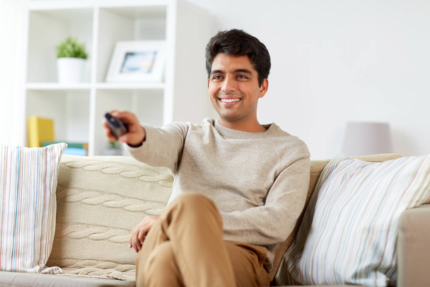 man with remote control watching tv at home - Foto, Imagem