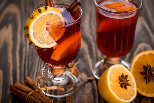 Hot mulled wine with spicy spices and orange. Lemon, cinnamon and cardamom on a dark wooden background. - Fotoğraf, Görsel
