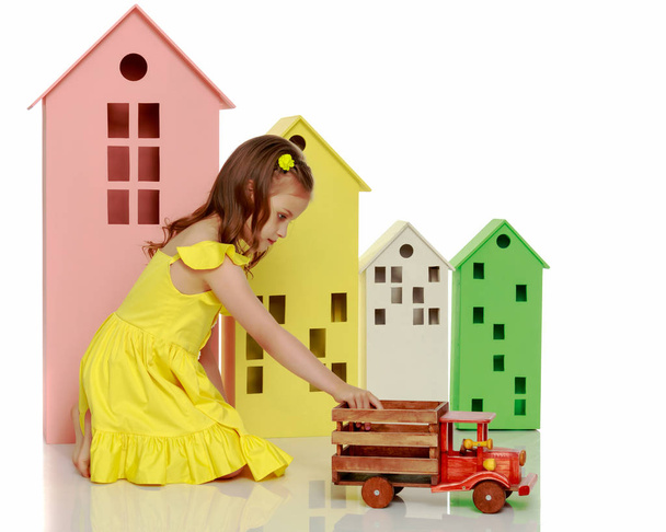 Little girl is playing with a wooden car. - Photo, Image
